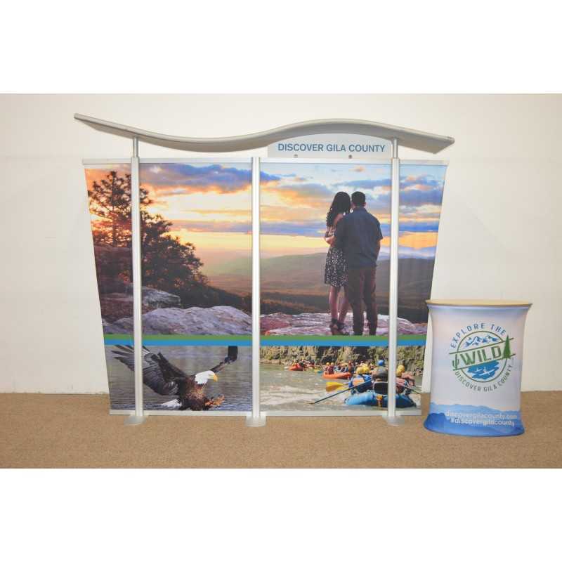 The 10ft Timberline Wave Canopy Tapered Kit 5 by Affordable Exhibit Displays features a nature-themed SEG fabric graphic reading “Discover Gila County,” plus a side stand with “Explore the Wild Gila County, AZ.” Images include a couple at sunset, rafting, and an eagle.