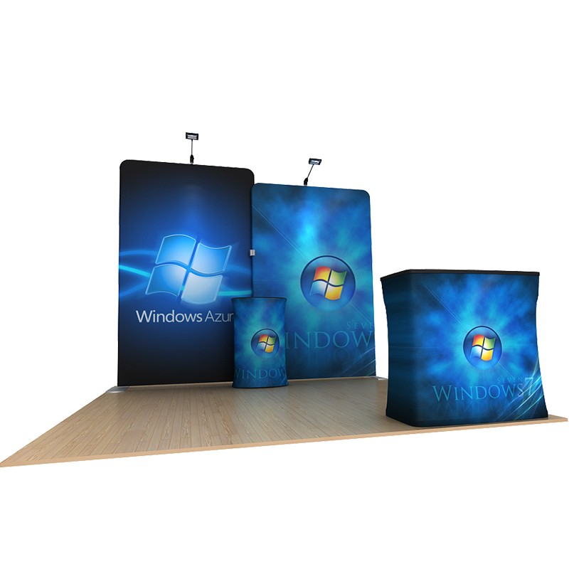The 10ft Waveline Media B-Series Scallop Kit B by Affordable Exhibit Displays features blue backgrounds, illuminated signs, a branded counter, and a tall tension fabric backdrop with the Windows logo on a wooden floor.