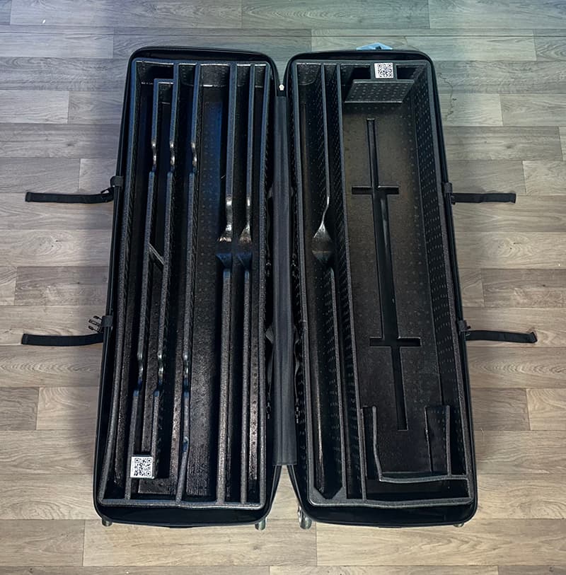 An open 20ft StraightLine FA2 Kit hard-shell carrying case by Affordable Exhibit Displays sits on a wood floor, showing foam inserts, compartments, straps, and QR code labels for secure storage of trade show booth parts.