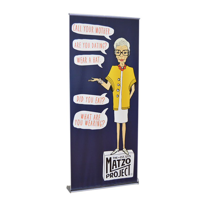 The Orient Standard Retractable Banner Stand displays an illustrated elderly woman in glasses and a yellow cardigan with speech bubbles: Call your mother, Are you dating? Wear a hat, Did you eat? What are you wearing? The Matzo Project logo is at the bottom.