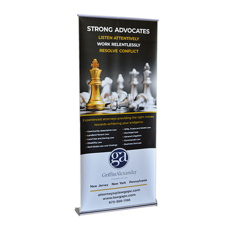 The Orient Standard Retractable Banner Stand displays chess pieces with a gold king, reading: STRONG ADVOCATES—Listen attentively, work relentlessly, resolve conflict—with custom graphics and Griffin Alexander law firm info below.