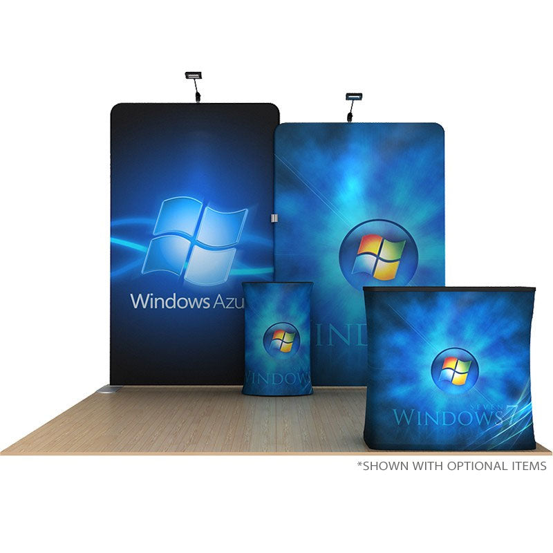 The 10ft Waveline Media B-Series Scallop Kit B by Affordable Exhibit Displays features blue panels with Windows Azure logos and digital designs, plus two front counters with Windows logos, all on a wooden floor under spotlights.