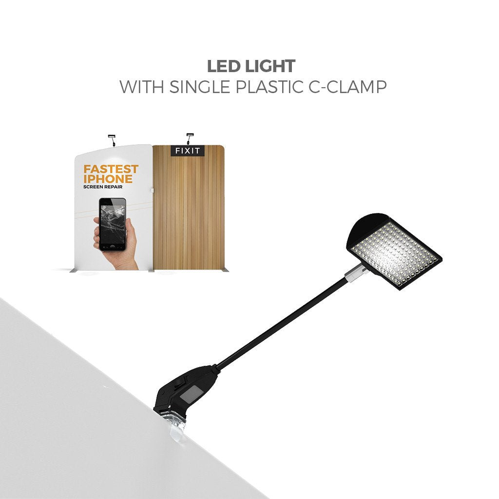 An LED light with a plastic C-clamp is attached to a surface. In the background, a booth displays the FixIt logo and sign using the 20ft Waveline Media M-Series Kit 01 by Affordable Exhibit Displays for FASTEST iPHONE SCREEN REPAIR.