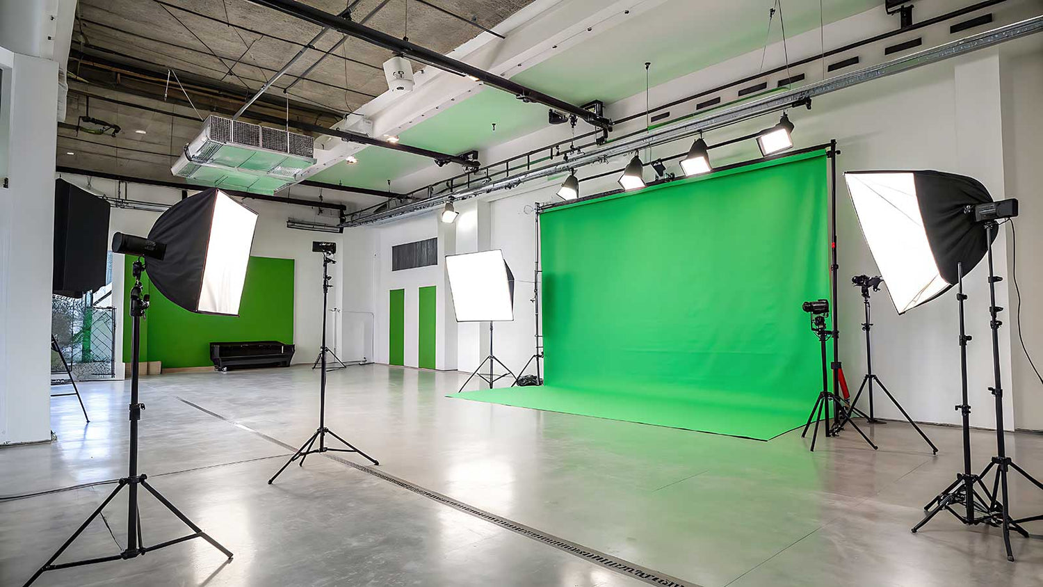 A studio with a green screen backdrop and lighting equipment ready for production use