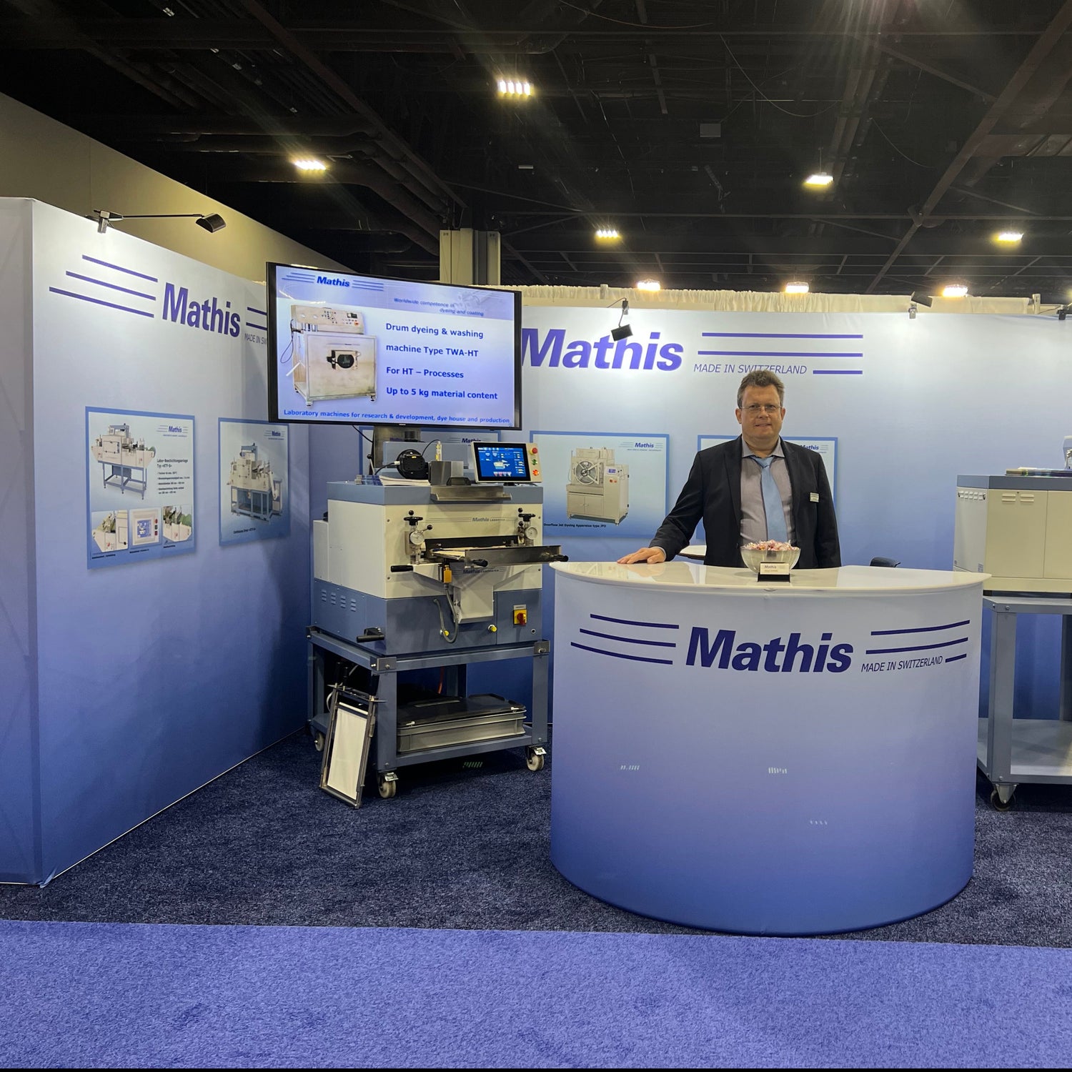 20ftx20ft Embrace tension fabric displays set up in an L shape with curved podium for attendee engagement.